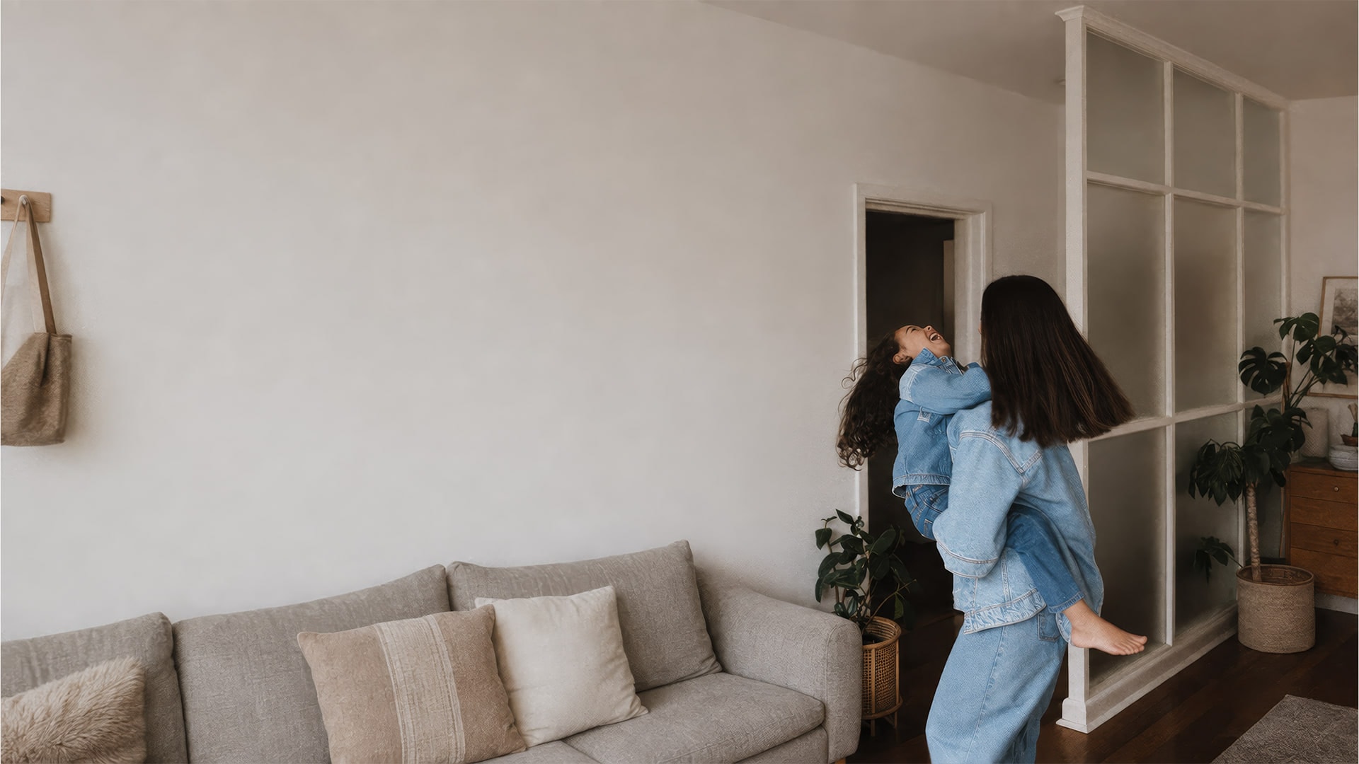 A mother lifting her laughing daughter up in her arms in a sunlit living room
