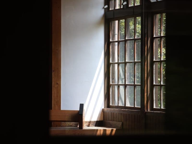Warm afternoon sunlight streaming through a large window onto wooden furniture in a calm room