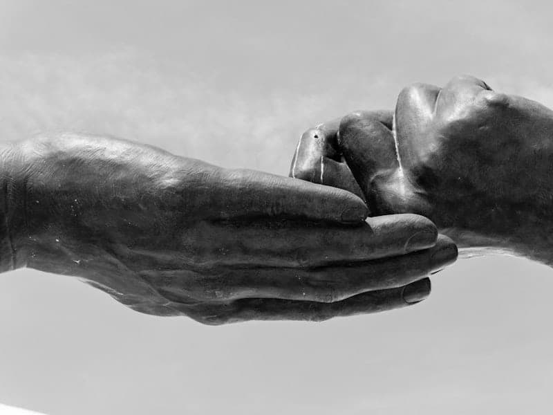 Two hands gently holding each other in warm light, conveying comfort and support